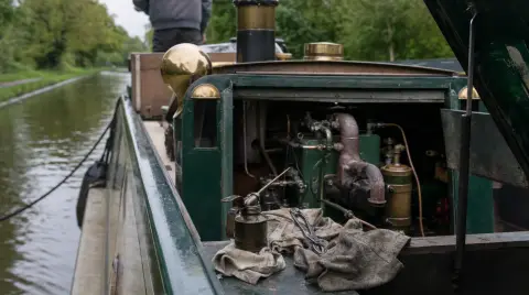 The engine hole of a narrowboat opened up for maintenance, an oil can and rags on the deck plates.