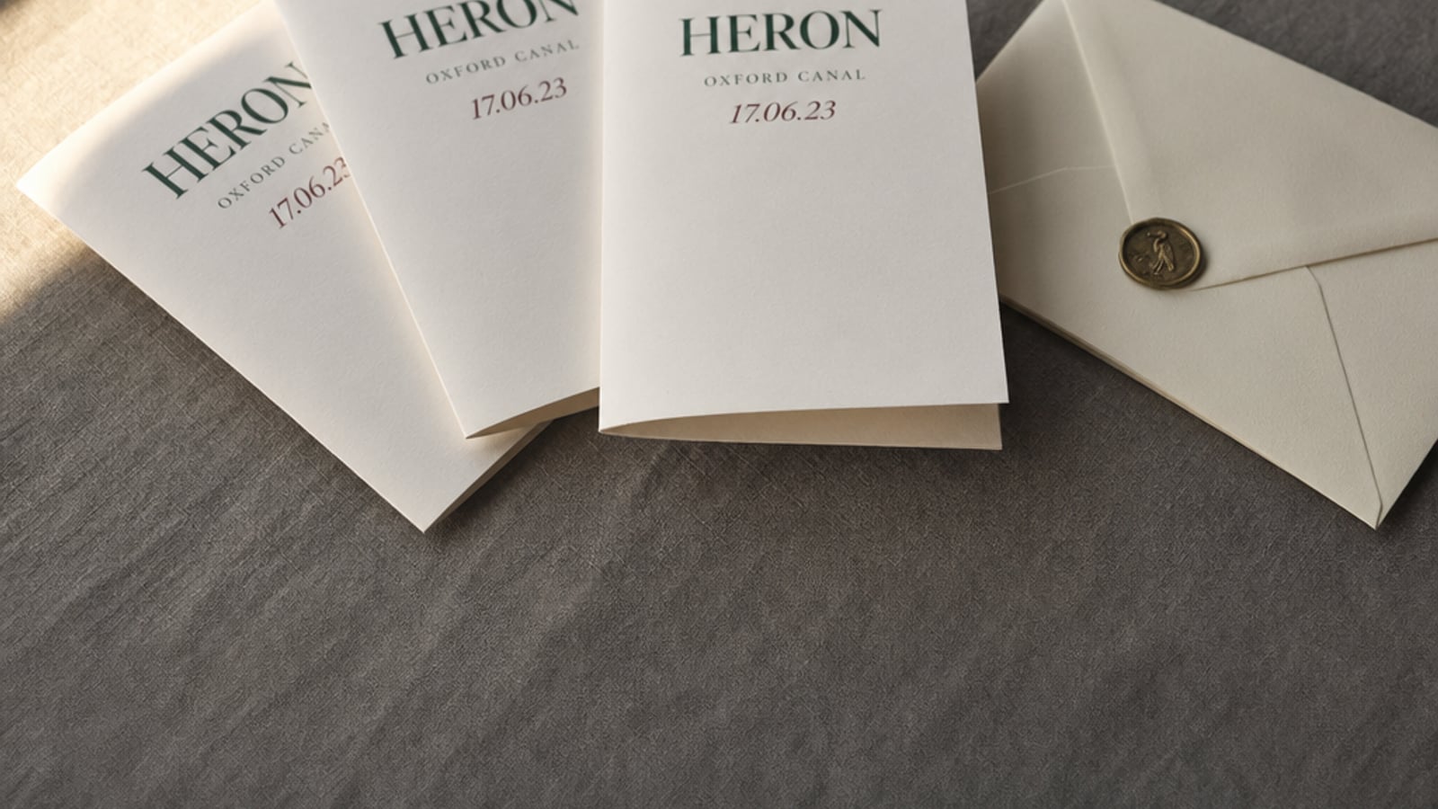 Three folded narrowboat greeting cards spread on smoke-grey linen with a wax-sealed cream envelope