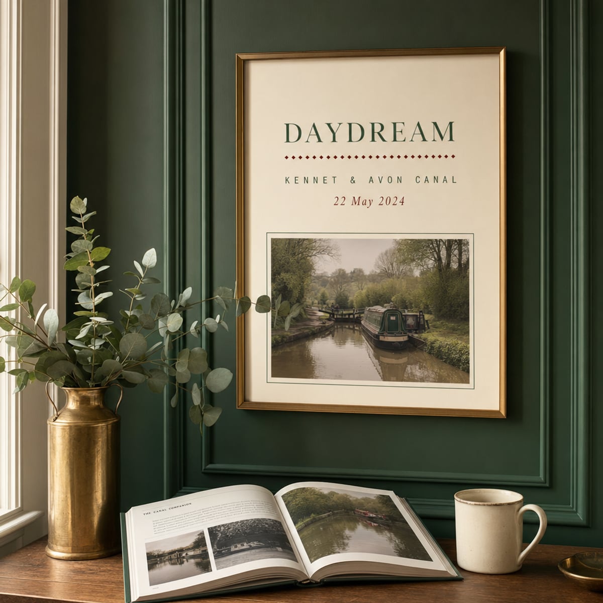 A framed personalised narrowboat name print on a panelled bottle-green wall, brass picture rail and eucalyptus stems nearby